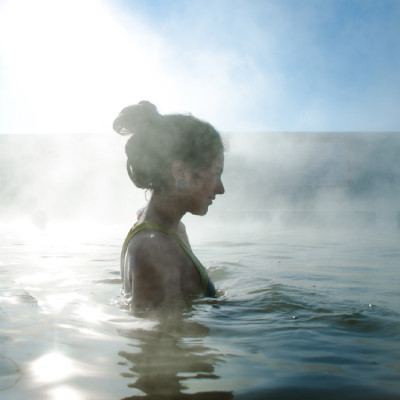 Image montrant partiellement une femme assise au bord d'une piscine et tenant dans sa main un thermomètre